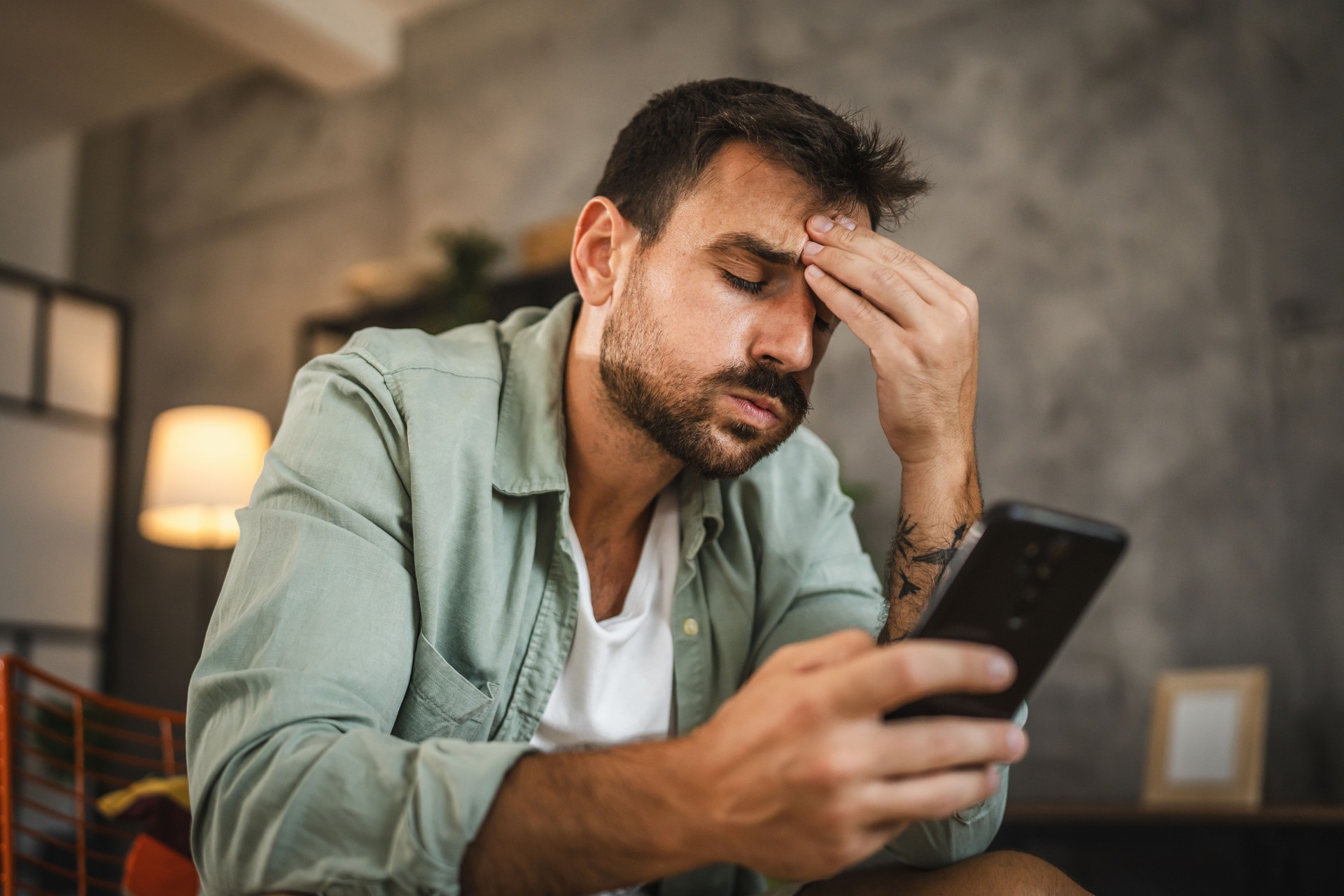 Portrait of adult furious man sit on chair and text sms on cellphone