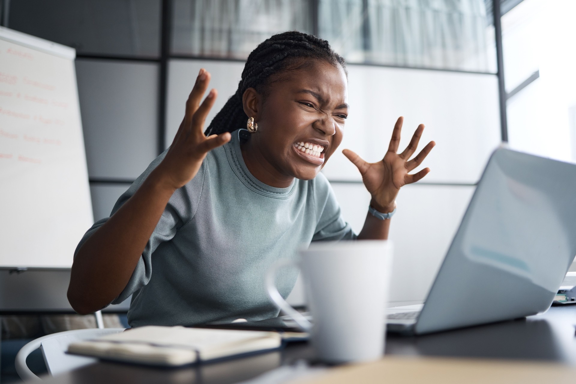 Shot of a young businesswoman looking angry while using a laptop in an office
